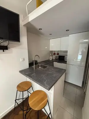 a kitchen with a sink and two bar stools at Parrot Apartment Main Station Cracow in Kraków