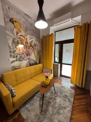 a yellow couch in a living room with a painting at Parrot Apartment Main Station Cracow in Kraków