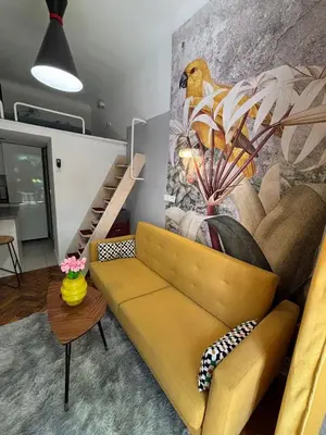 a living room with a yellow couch and a staircase at Parrot Apartment Main Station Cracow in Kraków