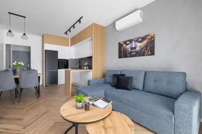 a living room with a blue couch and a table at Nowoczesny Apartament w Krakowie z Klimatyzowanym Salonem Dwa Miejsca Postojowe by Noclegi Renters in Kraków