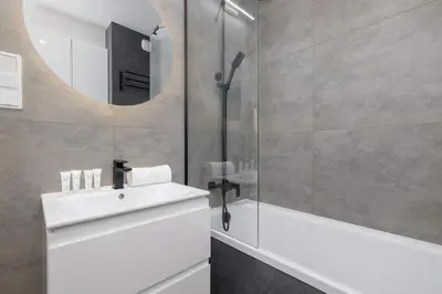 a bathroom with a sink and a mirror at Nowoczesny Apartament w Krakowie z Klimatyzowanym Salonem Dwa Miejsca Postojowe by Noclegi Renters in Kraków