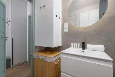 a bathroom with a white sink and a mirror at Nowoczesny Apartament w Krakowie z Klimatyzowanym Salonem Dwa Miejsca Postojowe by Noclegi Renters in Kraków