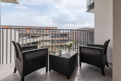a balcony with two chairs and a table with a view at Nowoczesny Apartament w Krakowie z Klimatyzowanym Salonem Dwa Miejsca Postojowe by Noclegi Renters in Kraków