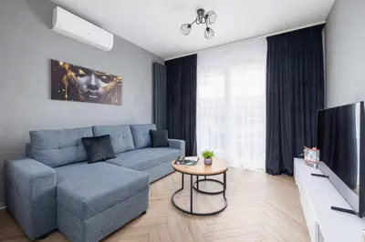 a living room with a blue couch and a tv at Nowoczesny Apartament w Krakowie z Klimatyzowanym Salonem Dwa Miejsca Postojowe by Noclegi Renters in Kraków