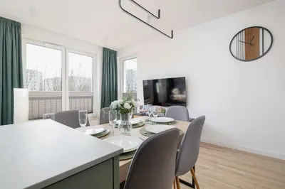 a dining room with a table and chairs and a television at Nowoczesny Rodzinny Apartament z Klimatyzacją i Parkingiem w Krakowie by Renters Prestige in Kraków