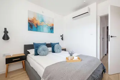 a white bedroom with a bed with blue pillows at Nowoczesny Rodzinny Apartament z Klimatyzacją i Parkingiem w Krakowie by Renters Prestige in Kraków