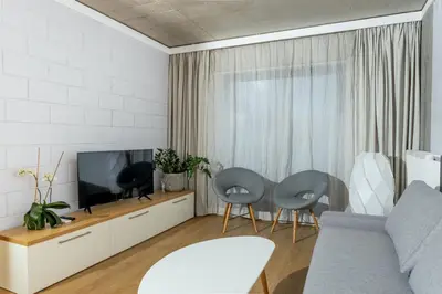 a living room with a tv and two chairs at Loft Place Oswiecim - Air Conditioning, City Center, Self Check-in in Oświęcim