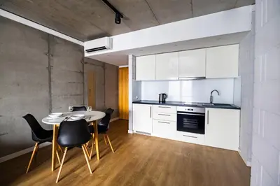 a kitchen with white cabinets and a table and chairs at Loft Place Oswiecim - Air Conditioning, City Center, Self Check-in in Oświęcim