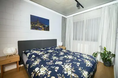 a bedroom with a bed with a blue and white comforter at Loft Place Oswiecim - Air Conditioning, City Center, Self Check-in in Oświęcim
