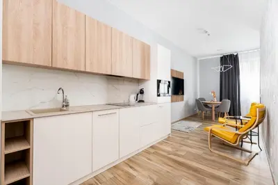 a kitchen with white cabinets and a yellow chair at Noble Residence Luxury Suites in Kraków