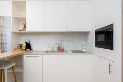 a white kitchen with a sink and a microwave at Noble Residence Luxury Suites in Kraków