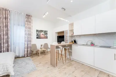 a kitchen with white cabinets and a table in a room at Noble Residence Luxury Suites in Kraków