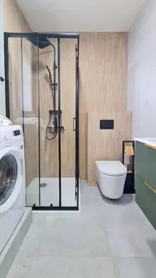 a bathroom with a washing machine and a toilet at Apartament 2A na ul Wiejskiej 32c in Oświęcim