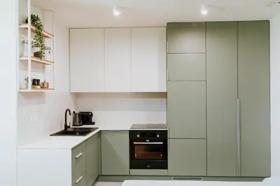 a kitchen with white cabinets and a black oven at Apartament 2A na ul Wiejskiej 32c in Oświęcim