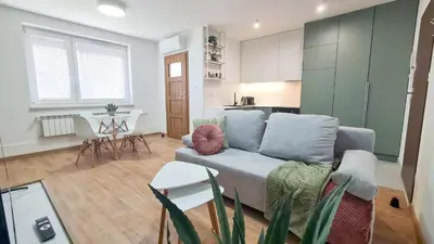 a living room with a couch and a kitchen at Apartament 2A na ul Wiejskiej 32c in Oświęcim