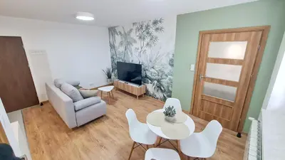 a living room with a table and a couch and a tv at Apartament 2A na ul Wiejskiej 32c in Oświęcim