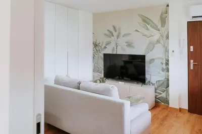 a living room with a white couch and a tv at Apartament 3A na ul Wiejskiej 32c in Oświęcim