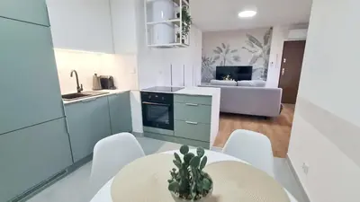 a kitchen with a table and chairs and a living room at Apartament 3A na ul Wiejskiej 32c in Oświęcim