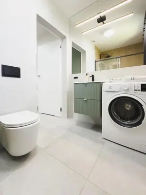 a bathroom with a washing machine and a toilet at Apartament 3A na ul Wiejskiej 32c in Oświęcim