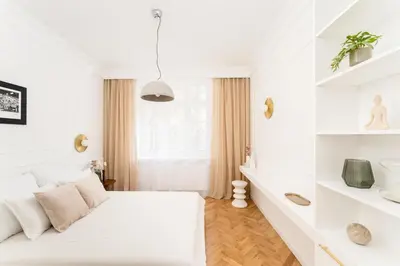 a white bedroom with a bed and shelves at Parkside Family Suite in Kraków