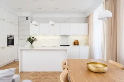 a kitchen with a wooden table and white cabinets at Parkside Family Suite in Kraków
