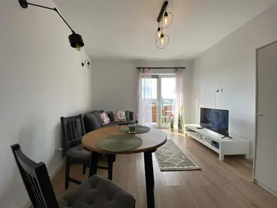 a living room with a table and a tv at Apartament Nad Stawem in Wadowice