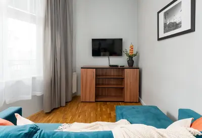 a living room with a tv on a wooden cabinet at Malila Premium Apartments Cracow Świętego Łazarza 3 in Kraków