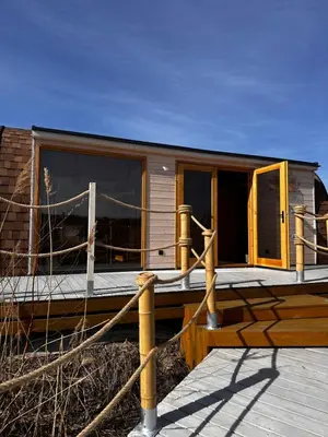 a small house with glass doors and a deck at Raj na Hektarach in Wysokie