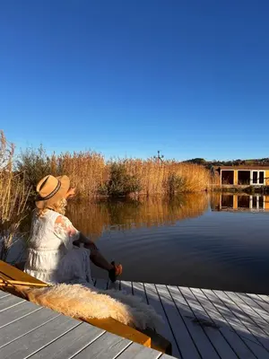 a woman sitting on a dock next to a body of water at Raj na Hektarach in Limanowa