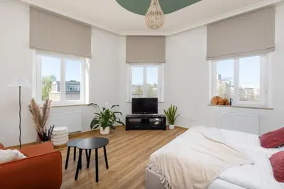 a white bedroom with a bed and a table at Katie's Apartment in Kraków