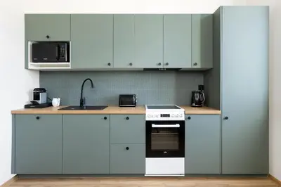 a kitchen with white cabinets and a stove and microwave at Katie's Apartment in Kraków