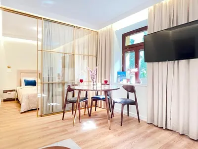 a living room with a table and chairs and a bedroom at Secret Garden Kraków - Wonderful City Centre Apartment - Ground Floor - Quiet Location in Kraków