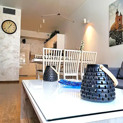 a living room with a table with a clock on the wall at Luxury Modern Apartment in Kraków