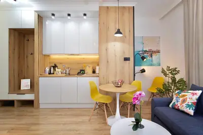 a kitchen and a living room with a table and yellow chairs at HolidayHome Kraków Center in Kraków