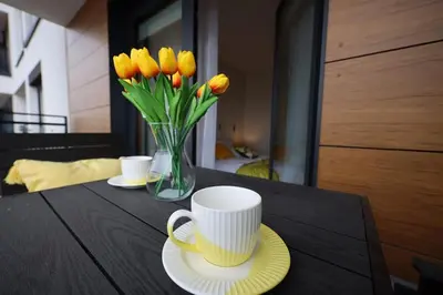 a table with a vase of yellow tulips and a vase of coffee at HolidayHome Kraków Center in Kraków