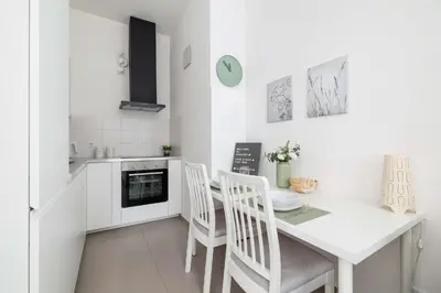 a white kitchen with a dining table and chairs at Modern Apartment with Air Conditioning and Parking in Cracow by Noclegi Renters in Kraków