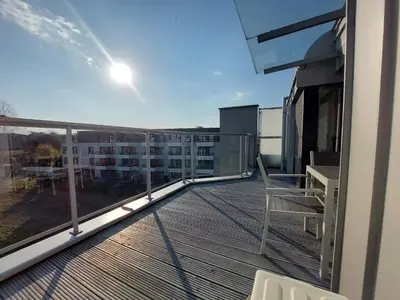 a balcony with a chair and a table on a building at Modern Apartment with Air Conditioning and Parking in Cracow by Noclegi Renters in Kraków