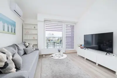 a living room with a gray couch and a large television at Modern Apartment with Air Conditioning and Parking in Cracow by Noclegi Renters in Kraków