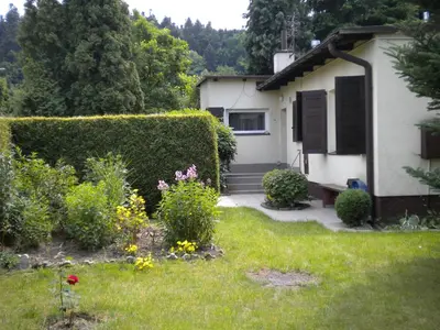 a house with a green hedge and flowers in the yard at Uroczy Domek Z Ogrodem I Tarasem in Myślenice