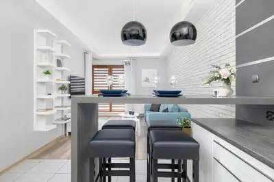 a kitchen with a long counter with stools at Nowoczesny & Klimatyzowany Apartament z Parkingiem by Noclegi Renters in Kraków