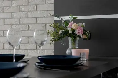 a table with two wine glasses and a vase of flowers at Nowoczesny & Klimatyzowany Apartament z Parkingiem by Noclegi Renters in Kraków