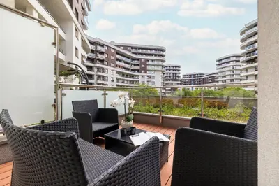 a balcony with chairs and a table with a view of buildings at Nowoczesny & Klimatyzowany Apartament z Parkingiem by Noclegi Renters in Kraków