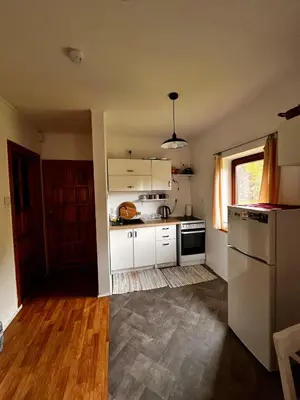 a kitchen with white cabinets and a refrigerator at Domek Ciśniawa in Sidzina