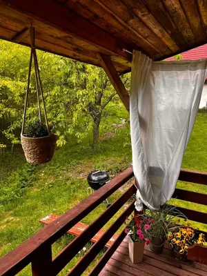 a porch with a bench with flowers and a net at Domek Ciśniawa in Sidzina