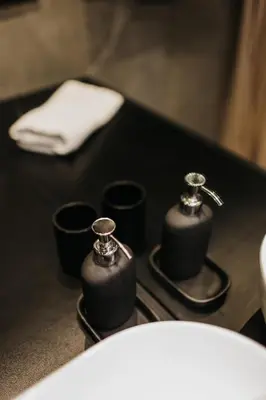 a black counter with two soap dispensers next to a toilet at Cubicle 72 Studio Big Terrace in Kraków