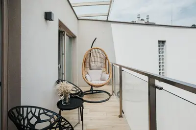 a balcony with a rattan chair and a table at Cubicle 72 Studio Big Terrace in Kraków