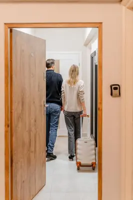 a man and a woman walking through a door with a suitcase at Bayview on Długa - By Hosty in Kraków