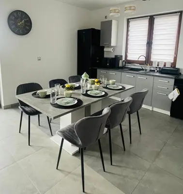 a kitchen with a table with chairs and a clock on the wall at Widokówka Kudłacze Domek z Jacuzzi in Pcim