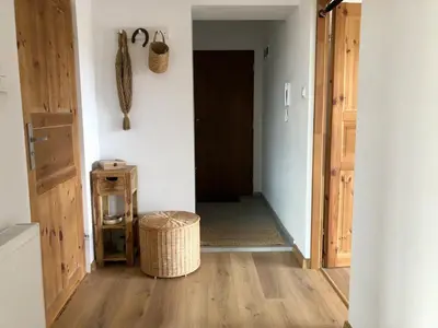 an open hallway with a door and a wicker stool at KrakowCharm private apartment Old Town in Kraków