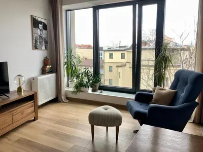 a living room with a blue chair and a large window at KrakowCharm private apartment Old Town in Kraków